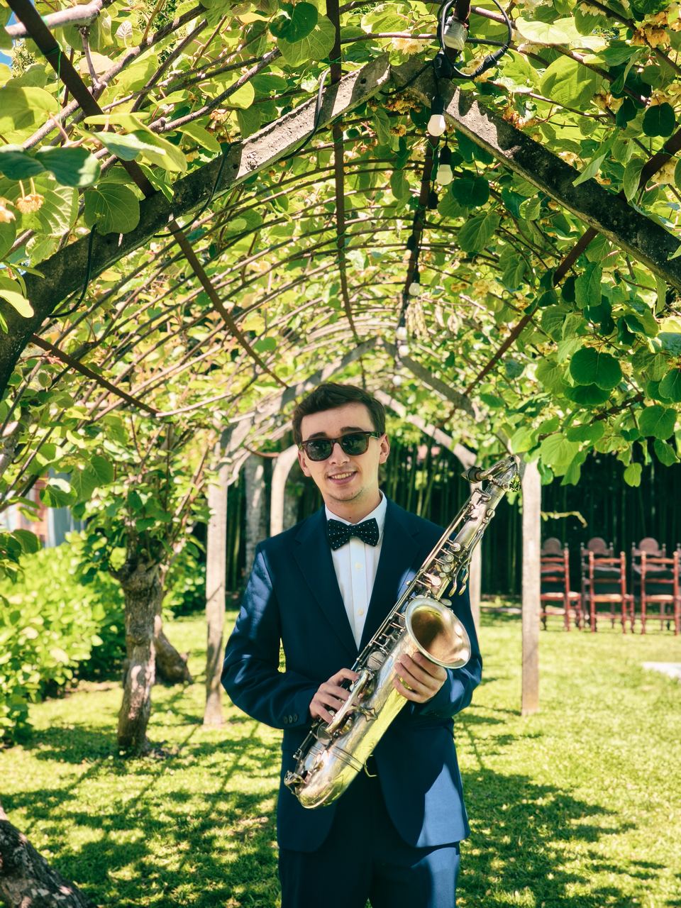 Francis Sax Plus, saxofonista, com o saxofone num jardim com cadeiras preparadas para uma cerimónia
